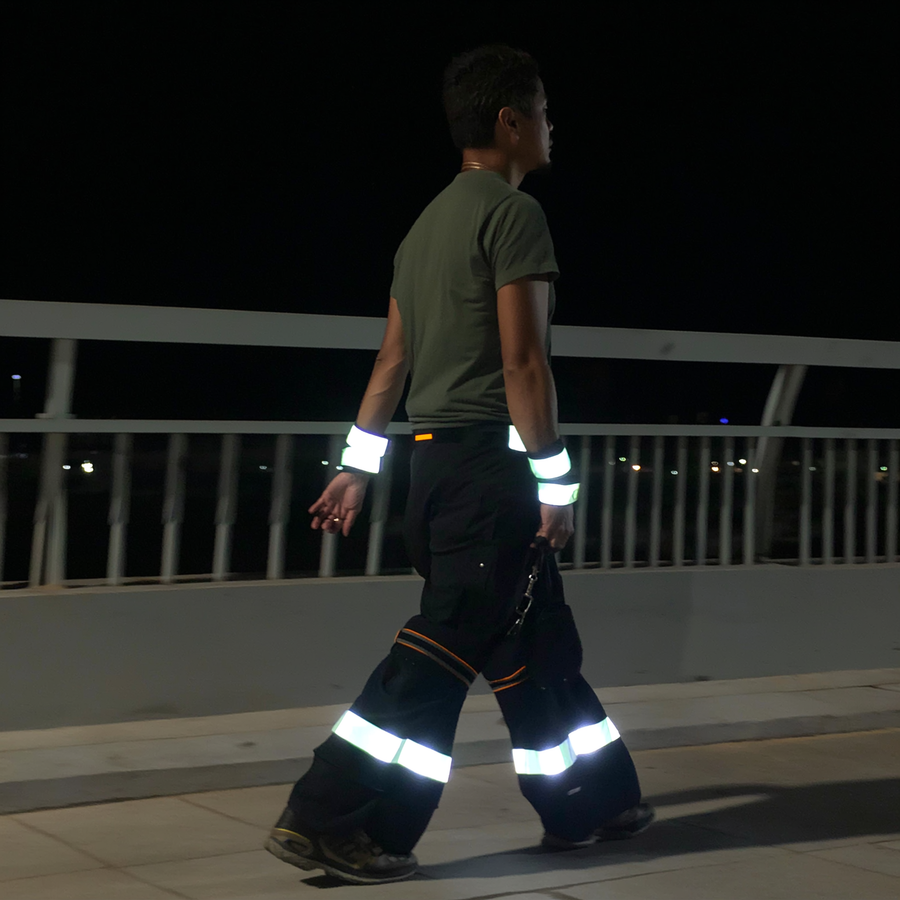 Câine negru pe o stradă rezidențială udă la amurg, cu zgardă reflectorizantă